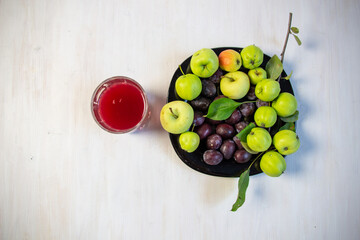 Compot made of plum and apple in glass on white wooden table