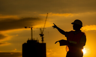 silhouette of engineer and construction site background at sunset