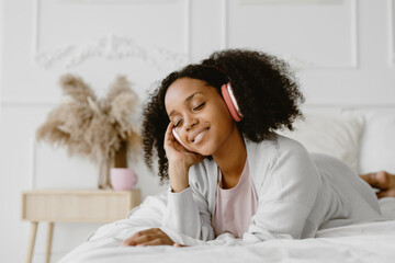 Young beautiful African-American woman relaxing and listening music using headphones.