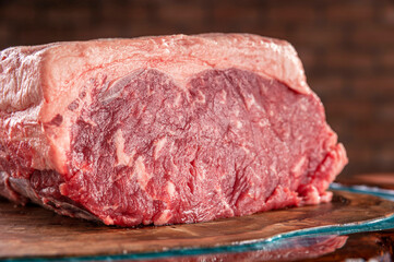 Raw strip loin beef (argentine chorizo) on a wood resined cutting board - Closeup.
