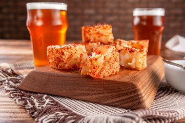 Tapioca dice with pepper jelly and glasses of beer on a wooden cutting board