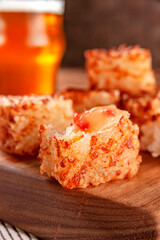 Tapioca dice with pepper jelly and glasses of beer on a wooden cutting board - Closeup.