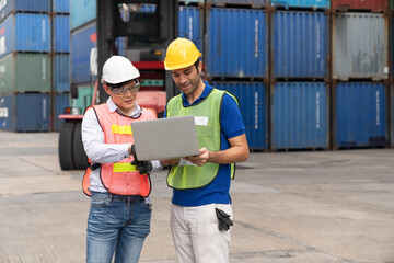 Engineer and foreman with laptop checking position loading Containers box from Cargo freight ship at Cargo container shipping