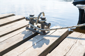 Bollard for mooring with a wound rope. Wooden pier.