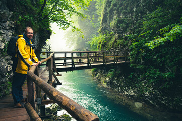 Hiking trail along the clear river through the Vintgar Gorge in Slovenia with man in yellow coat