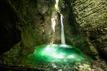 Chrystal clear waterfall in a cave flooded with sunlight and blue water