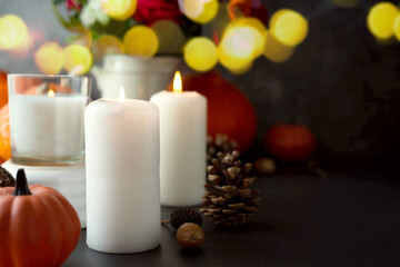 Fototapeta na wymiar Autumn creative background with candles, autumn flowers, pine cones and pumpkins. Dark moody, cozy fall