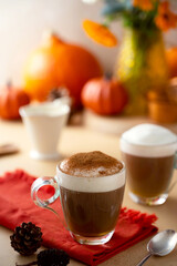 Two glass cups of pumpkin autumn latte warm drink with whipped cream. Autumn cozy beverage.