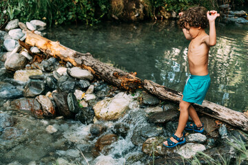 shirtless boy crossing the river