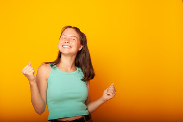 a teenage girl of American appearance on a yellow background in casual clothes with a bright smile on her face in a joyful mood. Emotions of joy, isolates, place for text