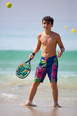 kid playing beach tennis on a sunny day