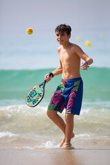 kid playing beach tennis on a sunny day