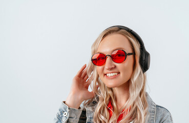 Naklejka premium Happy blonde in red glasses and headphones on a white background.