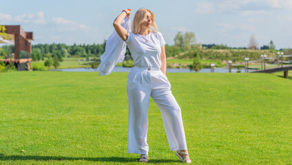 Blonde woman of plus size, American or European appearance walks at golf field, enjoying life. Young lady with excess weight, stylishly dressed at white .Natural beauty