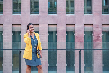 Caucasian business woman with mobile phone and computer outdoors.