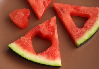 Triangular pieces of watermelon with heart cut from watermelon pulp in a brown cup, red watermelon