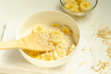  Oatmeal porridge with banana slices with a wooden spoon.