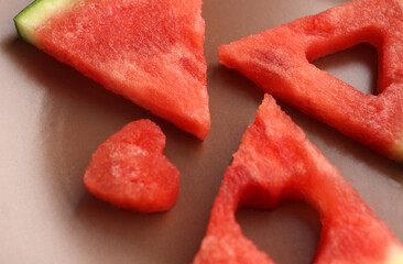 Triangular pieces of watermelon with heart cut from watermelon pulp in a brown cup, red watermelon