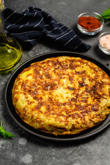 Traditional breakfast Spanish tortilla in cast iron skillet, dark background. Space for text.