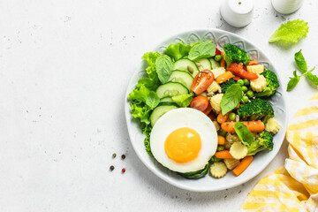 Salad vegetables fried egg bowl. Top view, space for text.