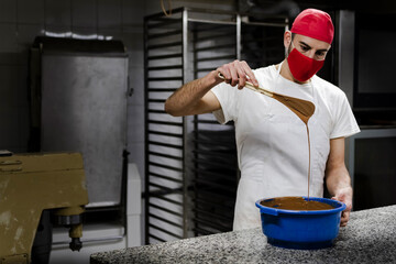 White male pastry chef in haute cuisine pastry design cap, stirring chocolate recipe master mix by...