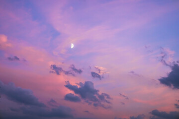 Majestic dusk. Twilight in the evening with gentle sunlight. Abstract nature background. Pink, purple, lilac colors of sky with dark clouds and young moon in sunset 