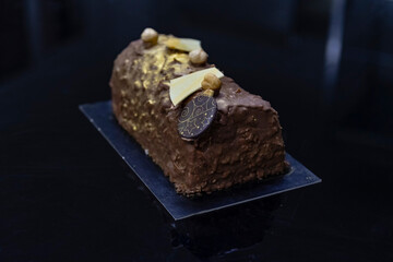 Dark chocolate dipped designer cake with gilding ready for sale. Haute cuisine sweet pastry shop