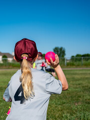 Blonde Caucasian girl with a hat throwing a baseball