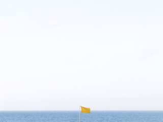 Fototapeta na wymiar Minimalist photo of a yellow flag with the sea in the background