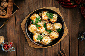 Georgian baked mushrooms with suluguni cheese on a wooden background