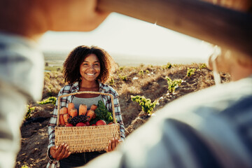 Smiling mixed race female farmer holding fresh vegetables 
