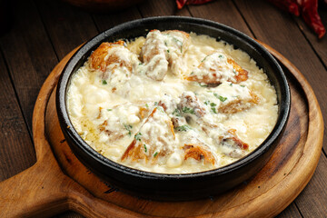 Georgian chkmeruli chicken dish with cream sauce on a wooden background