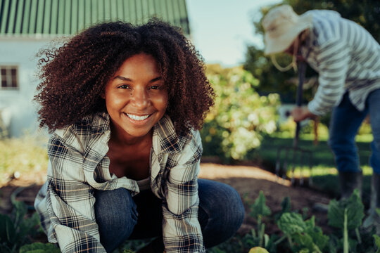 Beautiful smiling female farmer working in vegetable garden organising produce feeling active 