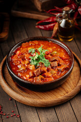 Georgian veal chashushuli stew with tomatoes on a wooden background