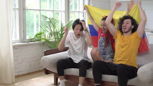 Emotional Colombian football fans watch TV at home.