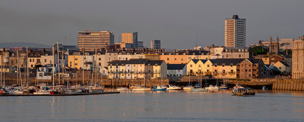 Plymouth, Devon, England, UK. 2021. Waterfront homes on the River Tamar, Plymouth. Evening light,  background the highrise buildings in the city centre.