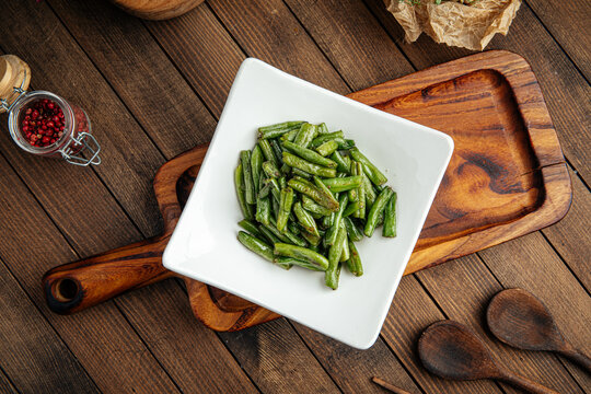 Plate of fried green string beans garnish on a wooden background