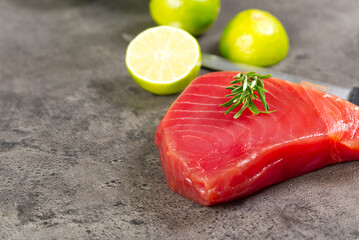 Raw tuna fillet steak with dill, lemon and spices in olive cutting board, ready for cooking