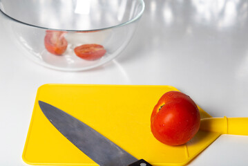 chopped tomatoes and knife on yellow cutting board.