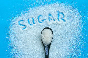 Sugar on blue background with tea spoon and sugar sign