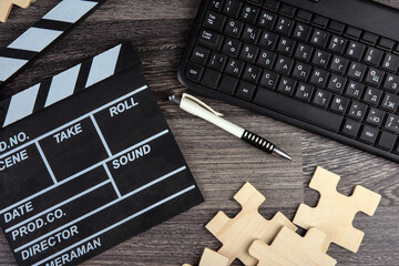 cinematic  clapper, pc keyboard, pen and puzzle pieces on a table