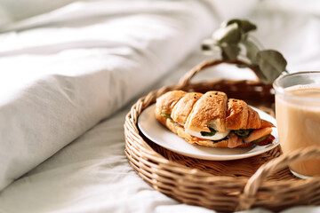 Breakfast in bed with croissant and coffee on tray