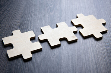 Three puzzle pieces in a row on a wooden background