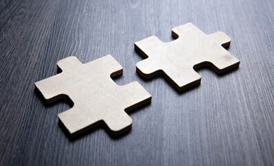 Fototapeta premium Two puzzle pieces in a row on a wooden background