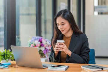 Young Asian businesswoman sitting at the office holding a coffee cup.