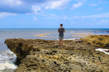 Man standing by the ocean on east side of Cozumel, Mexico