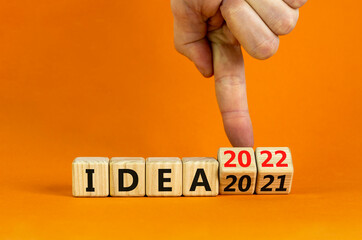 2022 idea new year symbol. Businessman turns a wooden cube and changes words 'Idea 2021' to 'Idea 2022'. Beautiful orange background, copy space. Business, 2022 idea new year concept.