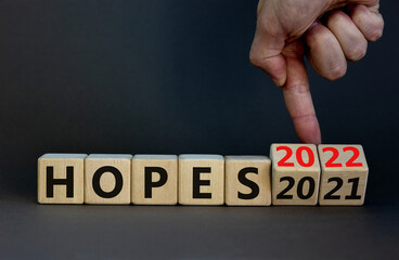 2022 hopes new year symbol. Businessman turns wooden cubes and changes words 'Hopes 2021' to 'Hopes 2022'. Beautiful grey background, copy space. Business, 2022 hopes new year concept.