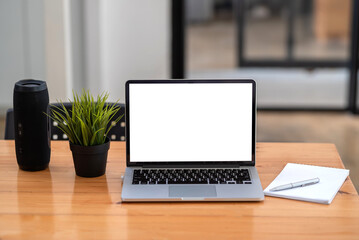 Fototapeta premium Laptop blank white screen with Bluetooth speaker notebook placed at office desk.