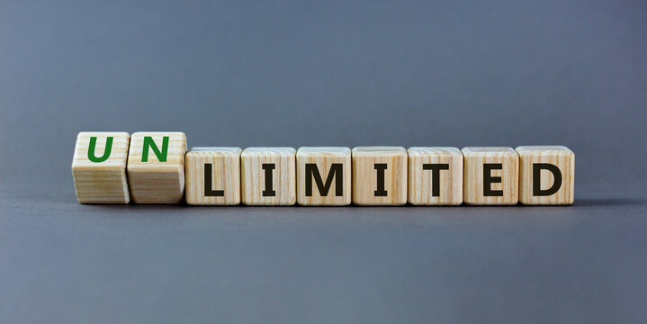Limited or unlimited symbol. Turned wooden cubes and changed words 'limited' to 'unlimited'. Grey background, copy space. Business, limited or unlimited concept.